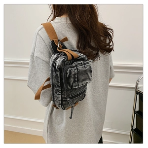 Detail der gewaschenen Denim-Brusttasche mit Vintage-Textur und braunem Segeltuchriemen
