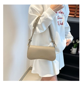 Detail of minimalist cream beige shoulder bag with pebble leather and knot strap detail