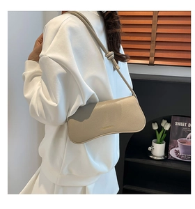 Detail of beige shoulder bag with knot strap and lychee grain leather texture
