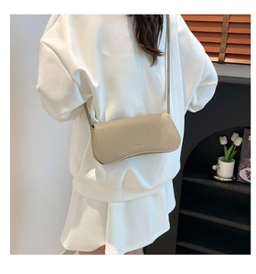 Chic beige underarm bag with lychee texture leather shown on model's shoulder