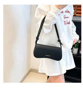 Detail of black leather underarm bag with double knot shoulder strap and logo text