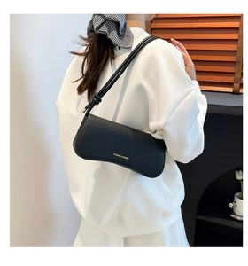 Close-up of black pebble leather crossbody bag with elegant gold logo and knot strap