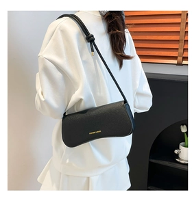 Detail showing black lychee texture leather shoulder bag with gold logo and knotted strap