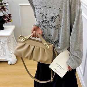 Chic ruched PU leather handbag in beige with gold buckle shown on shoulder by model