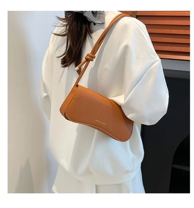 Detail of brown litchi pattern leather bag with gold fashion lettering and knot strap