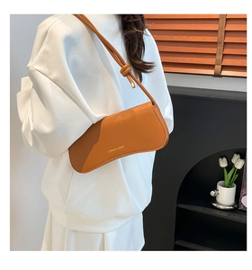 Close-up of brown litchi pattern leather baguette bag with knotted shoulder strap detail
