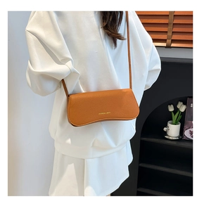 Close-up of brown lychee grain leather crossbody bag with gold fashion lettering