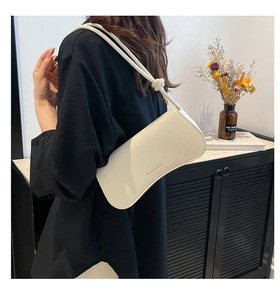Detail of white lychee texture underarm bag featuring knotted shoulder strap and logo