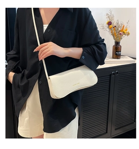 Close-up of white litchi pattern leather shoulder bag with gold printed fashion logo
