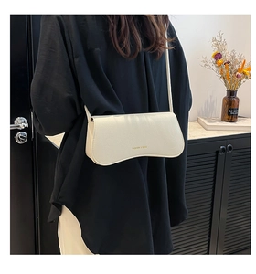 Detail of off-white crossbody bag with fashion logo and elegant lychee grain texture