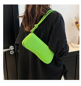 Detail of neon green underarm bag with lychee texture and FASHION & BAGS gold logo