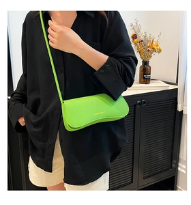 Close-up of bright green lychee grain leather handbag with magnetic flap and fine strap