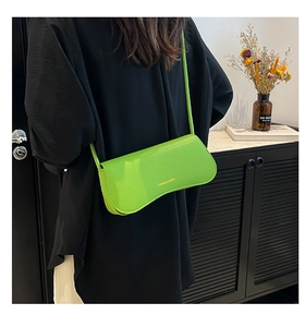 Green textured leather crossbody bag styled on model with minimalist interior background