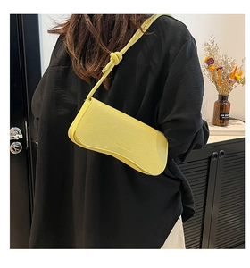 Detail of yellow lychee leather baguette bag with knotted shoulder strap on model