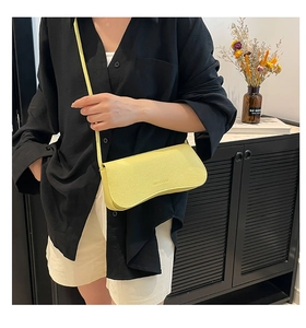 Detail of light yellow leather shoulder bag with embossed logo and elegant strap texture