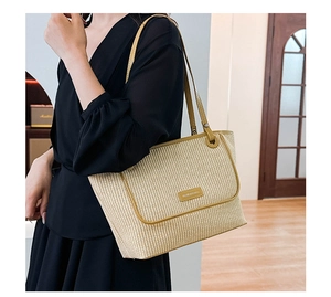 Detailed view of woven straw tote bag with yellow leather straps on female model