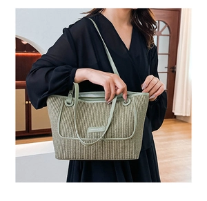 Detail of light green woven tote bag showing the texture and Fashion & Bags metal tag