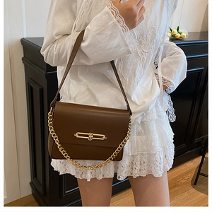 Detail view of coffee brown shoulder bag with golden metallic buckle and chain accent