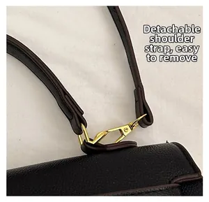 Detail of detachable shoulder strap with golden metal hook on black textured leather bag