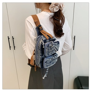Détail du sac de poitrine en jean vintage montrant le tissu délavé et les poches zippées