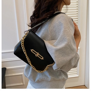 Detail of elegant black crossbody bag featuring a gold clasp lock and chunky metal chain