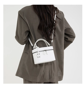 Detailed view of a white crocodile pattern handbag on a model in a dark brown blazer