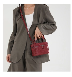 Detail of red crocodile texture box handbag with silver zippers and top handle