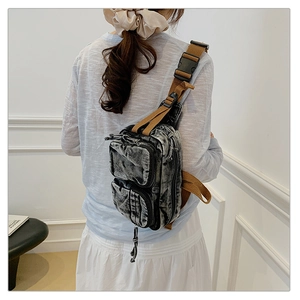 Détail du sac de poitrine en denim délavé avec fermetures éclair et sangle en nylon brun