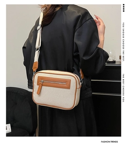 Dettaglio di una borsa a tracolla in tela beige con finiture in pelle marrone su un modello