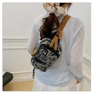 Gros plan du sac de poitrine en denim rétro avec zips et bandoulière en toile marron