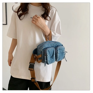 Détail d'un sac de poitrine en denim avec bandoulière brune porté par un mannequin