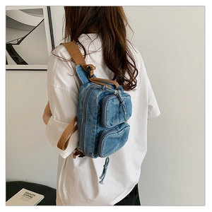 Vue arrière d'un sac bandoulière en denim bleu délavé avec sangle marron sur modèle