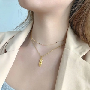 Close-up of golden double-layer necklace with Venus-style female torso art pendant