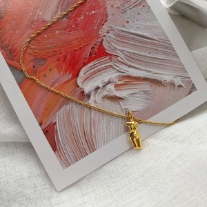 Collier doré minimaliste avec pendentif torse féminin abstrait sur fond artistique