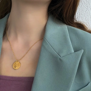 Detail of gold coin necklace with praying hands and One Day At A Time engraving