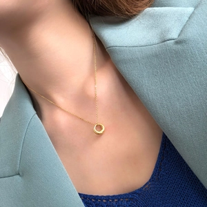Close-up of minimalist gold circular pendant necklace worn with a stylish blue blazer