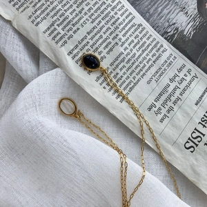 Retro golden necklaces with oval black and white stones on textured fabric