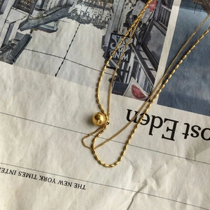 Double-layered gold bead necklace for women on vintage newspaper background