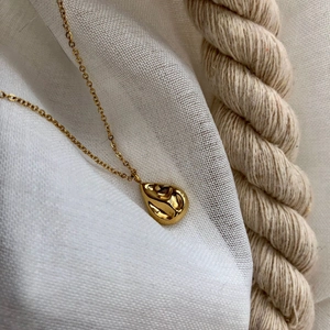 Collier à pendentif goutte dorée avec texture martelée sur fond de corde rustique