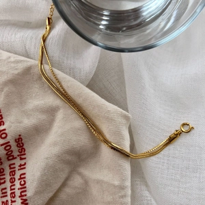 Detailed view of luxury gold snake bone chain bracelet with round spring clasp on fabric