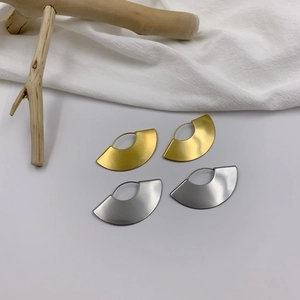 Minimalist geometric fan-shaped metal earrings in gold and silver finish on wood