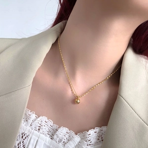 Detailed view of a golden minimalist sphere pendant on a refined bead chain necklace
