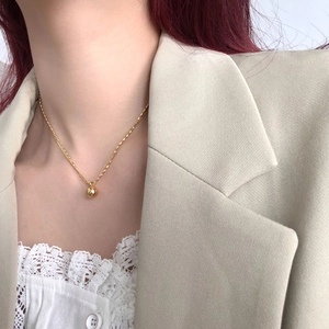 Close-up of minimalist double-layered gold ball pendant necklace on a female model