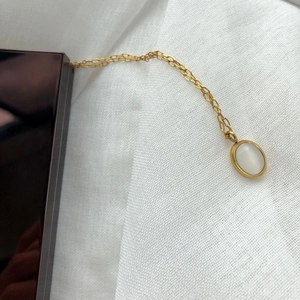 Detail of a vintage oval white agate pendant on a delicate gold chain necklace