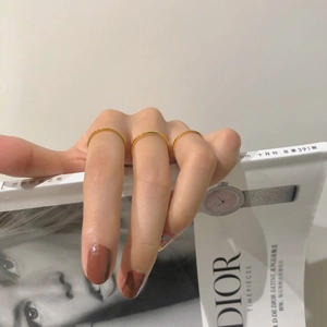 Close-up of minimalist thin gold stacking rings worn on fingers against a magazine background