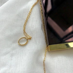 Close-up of a vintage gold oval necklace featuring a translucent white agate stone pendant