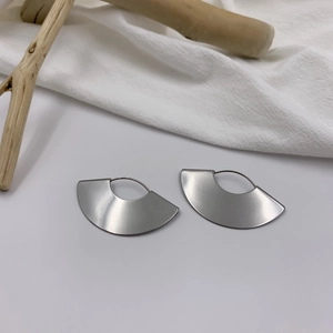 Detailed view of matte silver fan-shaped geometric drop earrings with a brushed metal finish