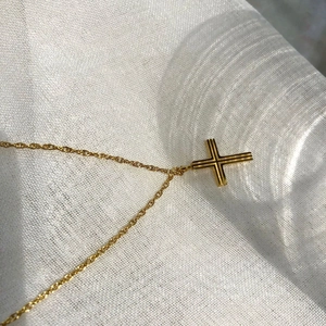 Minimalist gold cross necklace with textured vertical grooves on a fine twisted rope chain