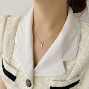Détail du collier rectangle en acier titane doré avec gravure de rose sur mannequin