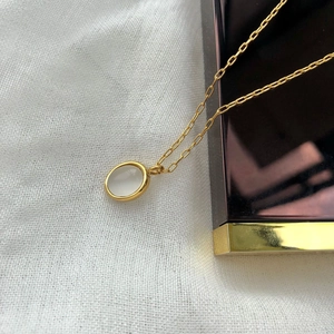 Detail of vintage gold necklace with oval white agate pendant on textured background